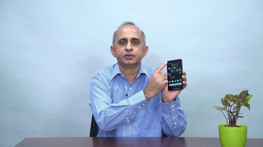 Pramit holding a phone and pointing to his app